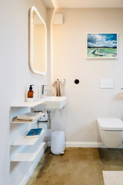 Das kleine Bad hat eine Dusche mit Fenster, Waschbecken, Toilette, Spiegel und Föhn.